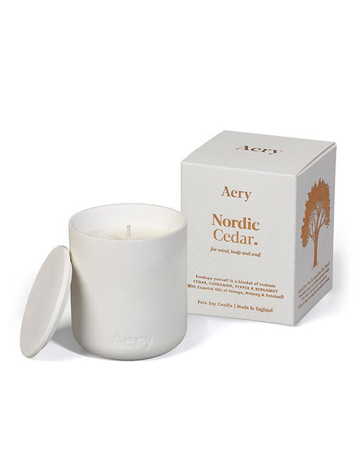 White Nordic Cedar candle by Aery displayed next to  product packing on white bacground 