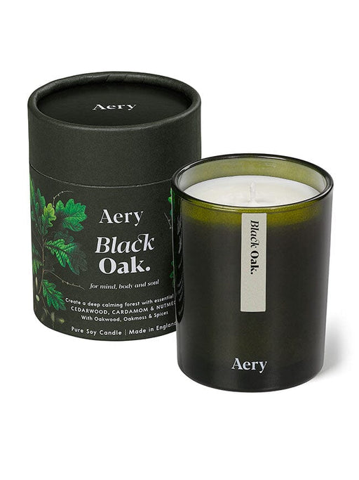 Green Black Oak candle displayed next to product packaging on white bacground 