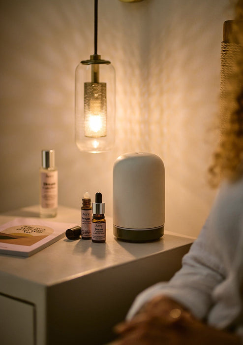Lilac Dream Catcher pulse point oil by Aery displayed next to dream Catcher fragrance oil and pillow spray by Aery placed on bedside table 