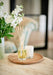 Citrus Tonic diffuser by aery displayed next to citrus tonic candle and vase of white flowers 